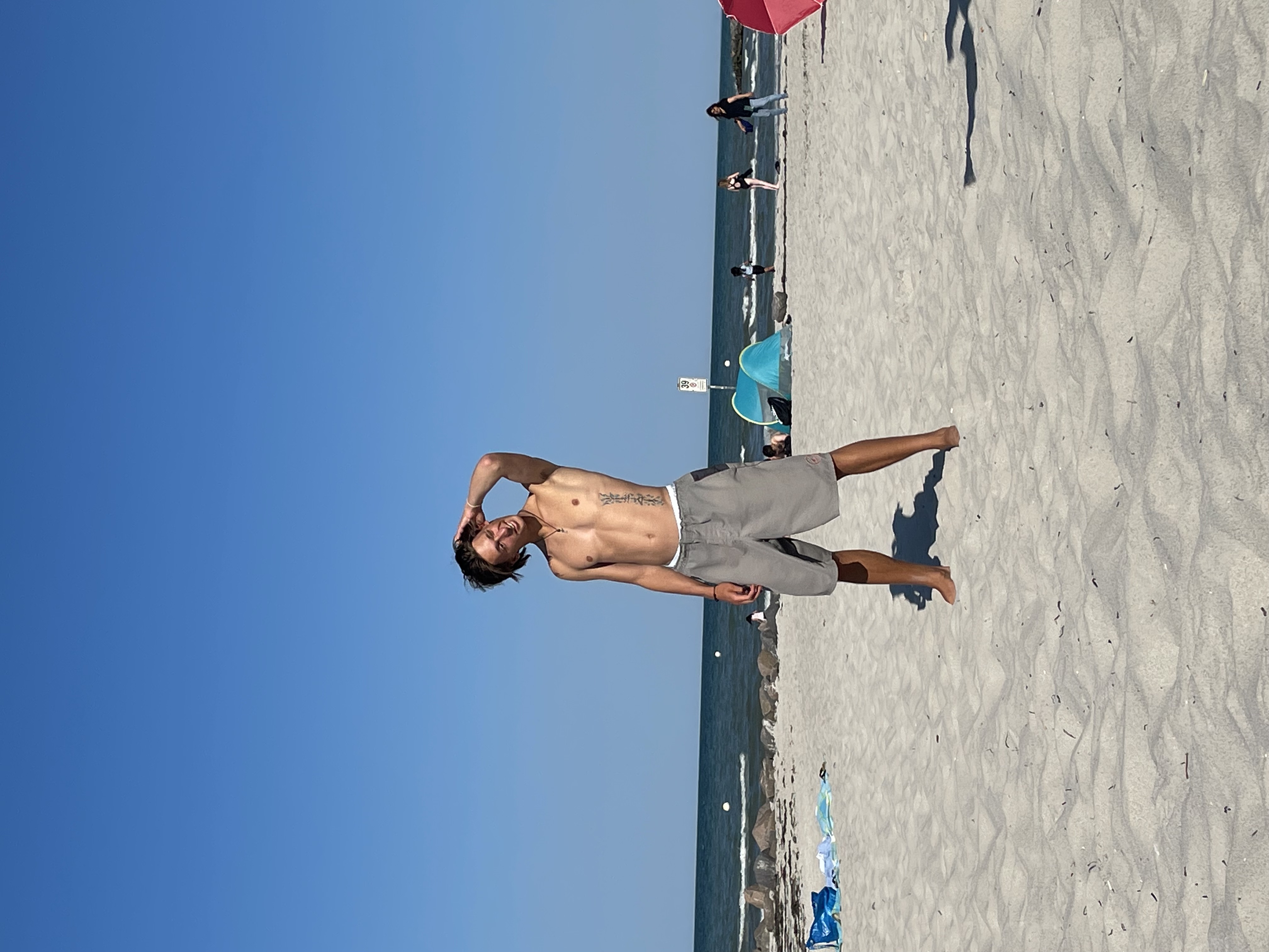 NOtide Gründer Eddy am Strand gebräunt mit Tattoo und Boardshorts